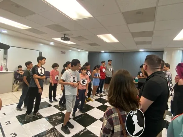 Actividad grupal sobre un tablero de ajedrez de gran formato.