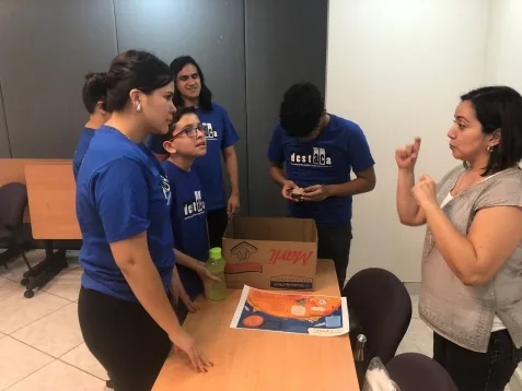 Participantes con playeras de DESTACA durante un taller con materiales didácticos.
